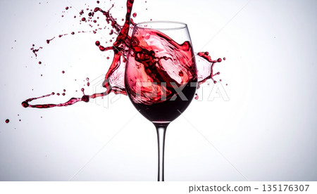 A picture of fresh red wine being poured into a wine glass, with beautiful droplets of mist splashing against a white background. A picture of fresh red wine being poured into a wine glass, with beautiful droplets of mist splashing against a white background. 135176307