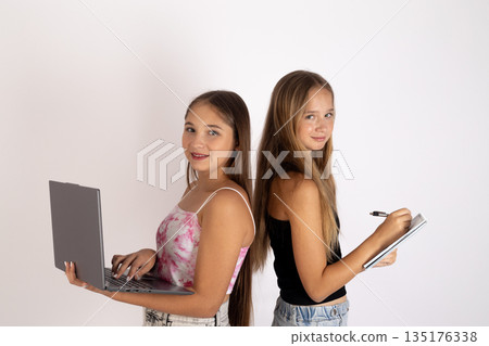 Two girls standing back to back 135176338