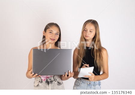 Two girls with laptops standing 135176340