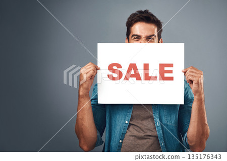 Man, sale and billboard poster for advertising, marketing or branding against a grey studio background. Male person or realtor holding board or sign for sales announcement, notice or advertisement 135176343