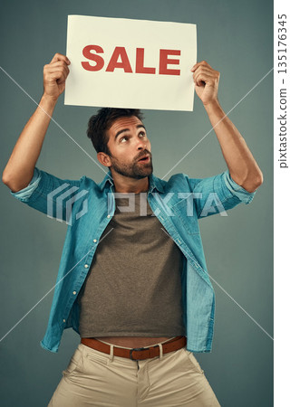 Man, hands and sale on poster for advertising, marketing or branding against a grey studio background. Male person or realtor holding board, sign or billboard for sales announcement or advertisement 135176345
