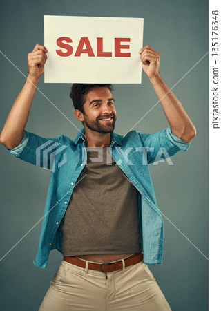 Happy man, sale and billboard poster for advertising, marketing or branding against a grey studio background. Male person or realtor holding board or sign for sales announcement or advertisement 135176348