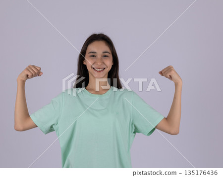 Strong woman in a green shirt showing her biceps 135176436