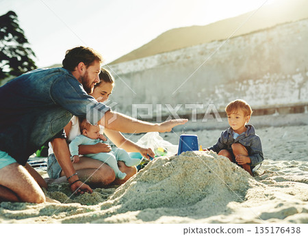 Sandcastle help, parents and children at the beach with bonding, love and support. Baby, mom and dad together with kids playing in the sun with happiness and smile by the ocean and sea with family Sandcastle help, parents and children at the beach with bonding, love and support. Baby, mom and dad together with kids playing in the sun with happiness and smile by the ocean and sea with family 135176438
