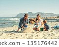 Sandcastle building, parents and children at beach with bonding, love and support. Baby, mom and dad together with kids playing in the sun with mockup space and smile by the ocean and sea with family 135176442