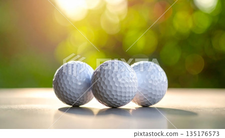 A close-up image of a white golf ball on a ball tee against a lush green lawn. A close-up image of a white golf ball on a ball tee against a lush green lawn. 135176573