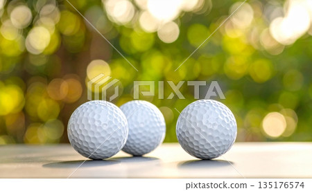 A close-up image of a white golf ball on a ball tee against a lush green lawn. 135176574