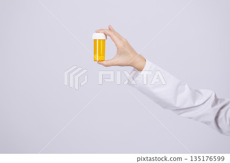 Hand holding a yellow medicine pill bottle Hand holding a yellow medicine pill bottle 135176599