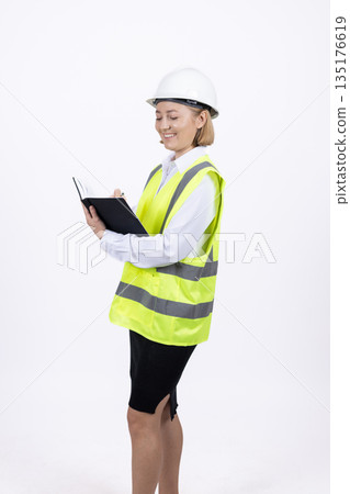 Female engineer in hardhat writing on clipboard 135176619