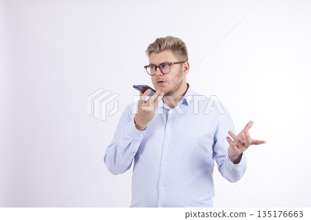 Man in a light blue shirt talking on a smartphone Man in a light blue shirt talking on a smartphone 135176663