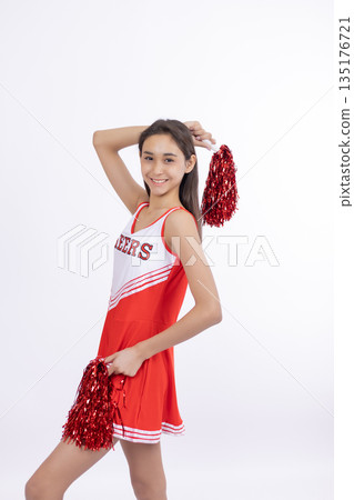 Cheerful cheerleader girl jumping with red pom-poms. 135176721