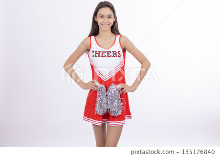 Girl in a cheerleader uniform holding red pom-poms 135176840