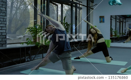 People practicing yoga together in a modern studio People practicing yoga together in a modern studio 135176860