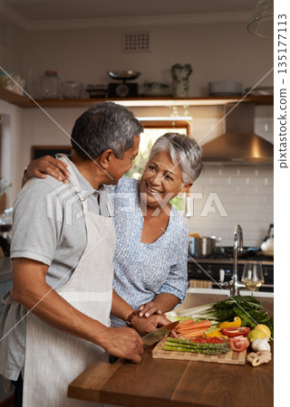 Happiness, vegetables and old man with woman in kitchen, embrace and healthy marriage bonding in home for dinner. Love, help and cooking, senior couple with smile, hug and happy time in retirement. Happiness, vegetables and old man with woman in kitchen, embrace and healthy marriage bonding in home for dinner. Love, help and cooking, senior couple with smile, hug and happy time in retirement. 135177113