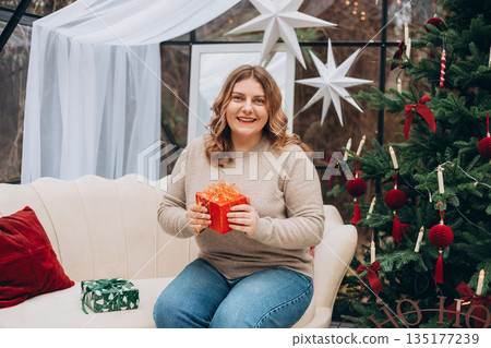 Merry Christmas, Happy Holidays banner. Cheerful pretty young woman having got a Christmas presents Merry Christmas, Happy Holidays banner. Cheerful pretty young woman having got a Christmas presents 135177239