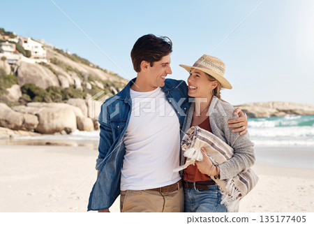 Love, happy couple at the beach and walking together hugging on seashore, Summer vacation or holiday break, adventure or traveling journey and young people walk at sea for fresh air with blue sky 135177405