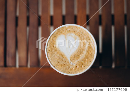 Cup of coffee on the wooden table with latte art. Street coffee, top view. Coffee in a white cup with latte art. Cup of coffee on the wooden table with latte art. Street coffee, top view. Coffee in a white cup with latte art. 135177696
