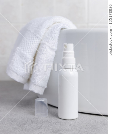 White cosmetic spray bottle on grey stone near white bath towel and basin close up, mockup White cosmetic spray bottle on grey stone near white bath towel and basin close up, mockup 135178086
