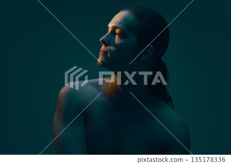 Male profile portrait with lifted chin on dark background. 135178336