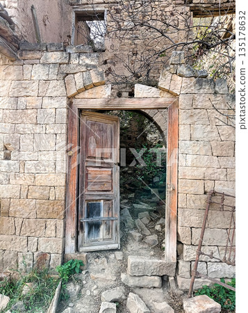 A wooden door is open in front of a stone wall 135178632
