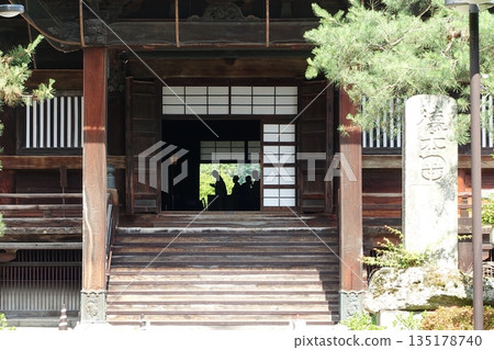 Japanese temple main hall entrance and silhouette of worshippers Japanese temple main hall entrance and silhouette of worshippers 135178740