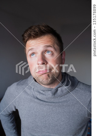 Uncertain male person looking up with hesitation, thinking or feeling skeptical. 135178899