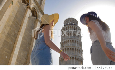Two young smiling women walking to the Leaning Tower of Pisa Two young smiling women walking to the Leaning Tower of Pisa 135178952