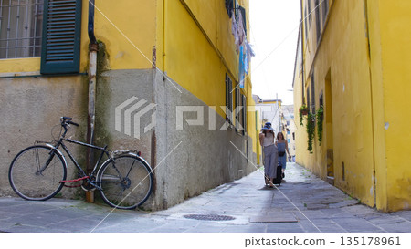 Two young excited women walking through the narrow yellow streets with luggage 135178961