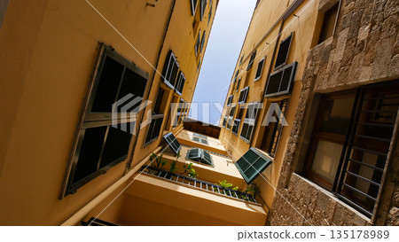 A view of a roofs from the narrow alley - yellow buildings and balcony 135178989