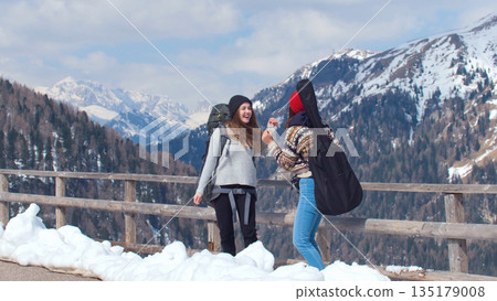 Two young traveling excited women tourist standing on a background of mountains and laugh 135179008