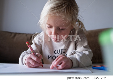 Preschool child doing homework and practicing writing skills, early education concept. Preschool child doing homework and practicing writing skills, early education concept. 135179390