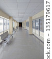 Empty Modern Hospital Hallway with Metal Benches and Bright Windows 135179617