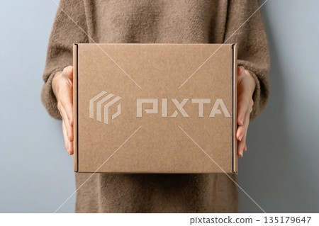 Woman with blank cardboard box on white background, top view. Mockup for design 135179647