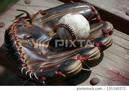 木凳上放著棒球手套和棒球。 135180372