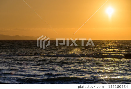 Friends enjoying a sunny beach day while building a sandcastle near the ocean in the afternoon 135180384