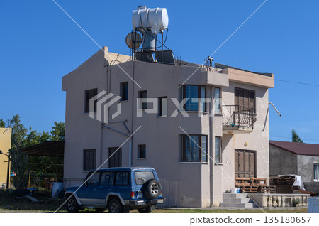 Charming two-story house in rural setting with water tank and sunny blue sky 135180657
