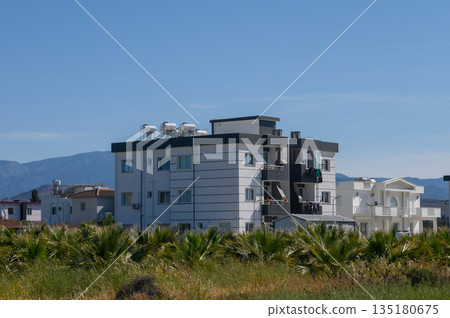 Modern residential buildings contrast with nature in a scenic landscape under clear blue skies Modern residential buildings contrast with nature in a scenic landscape under clear blue skies 135180675
