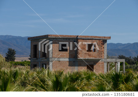 Old brick structure stands alone amidst lush greenery in a quiet landscape under a clear blue sky Old brick structure stands alone amidst lush greenery in a quiet landscape under a clear blue sky 135180681