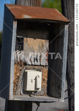 Weathered utility box reveals layers of nature and time in a tranquil outdoor setting during golden hour lighting Weathered utility box reveals layers of nature and time in a tranquil outdoor setting during golden hour lighting 135180710