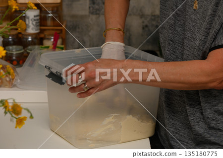 Creating homemade dough while wearing gloves in a cozy kitchen filled with fresh flowers and warm colors Creating homemade dough while wearing gloves in a cozy kitchen filled with fresh flowers and warm colors 135180775