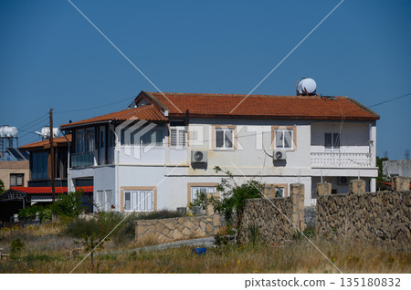 Charming rustic house with a red roof set against a clear blue sky showcasing the essence of countryside living in early afternoon light Charming rustic house with a red roof set against a clear blue sky showcasing the essence of countryside living in early afternoon light 135180832