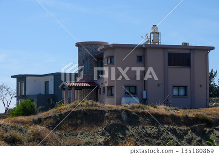 Modern hillside home with stone accents and serene surroundings in bright afternoon sunlight 135180869