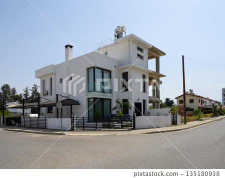 Modern architecture showcases a stylish residence at a tranquil intersection under a clear sky in suburban bliss Modern architecture showcases a stylish residence at a tranquil intersection under a clear sky in suburban bliss 135180938
