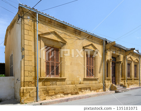 Historic yellow stone building stands proudly under a clear blue sky in quiet neighborhood with intricate architectural 135181071