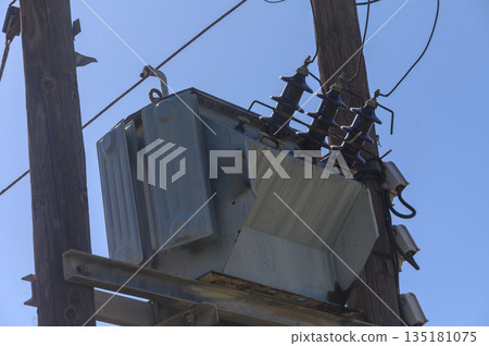 Electric transformation station high above, serving power to the bustling neighborhood below in bright daylight Electric transformation station high above, serving power to the bustling neighborhood below in bright daylight 135181075