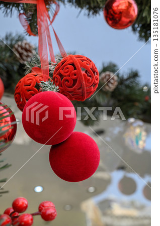 Decorative red ornaments hang from a festive tree, capturing the spirit of celebration during the winter holiday season Decorative red ornaments hang from a festive tree, capturing the spirit of celebration during the winter holiday season 135181076