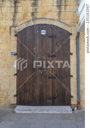 Rustic wooden door with iron hardware in an old stone wall, hinting at hidden treasures within the historic building Rustic wooden door with iron hardware in an old stone wall, hinting at hidden treasures within the historic building 135181097