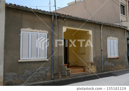 Charming weathered house with sunlit entrance showcasing rustic beauty in a quiet street 135181129