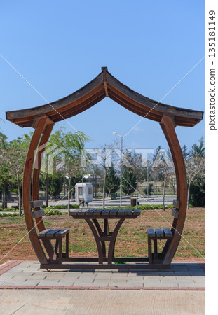 Relaxing wooden pavilion invites visitors to unwind in a serene park during a sunny day Relaxing wooden pavilion invites visitors to unwind in a serene park during a sunny day 135181149