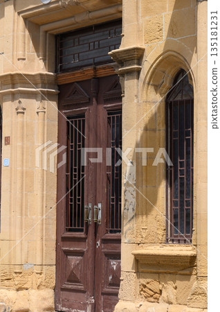 Historic wooden doors invite curiosity at a charming stone facade under a warm sunlit sky in a picturesque town Historic wooden doors invite curiosity at a charming stone facade under a warm sunlit sky in a picturesque town 135181231